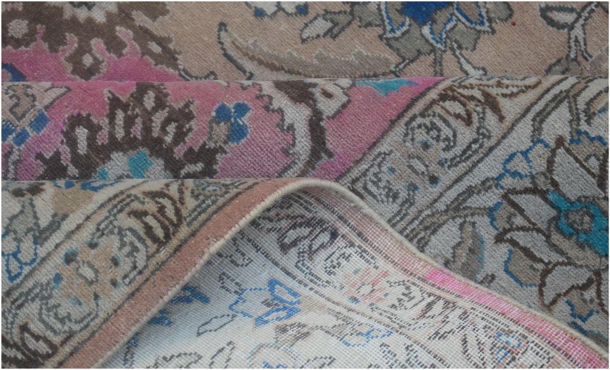A close-up of a vintage Persian wool rug featuring intricate floral patterns in pink and blue.