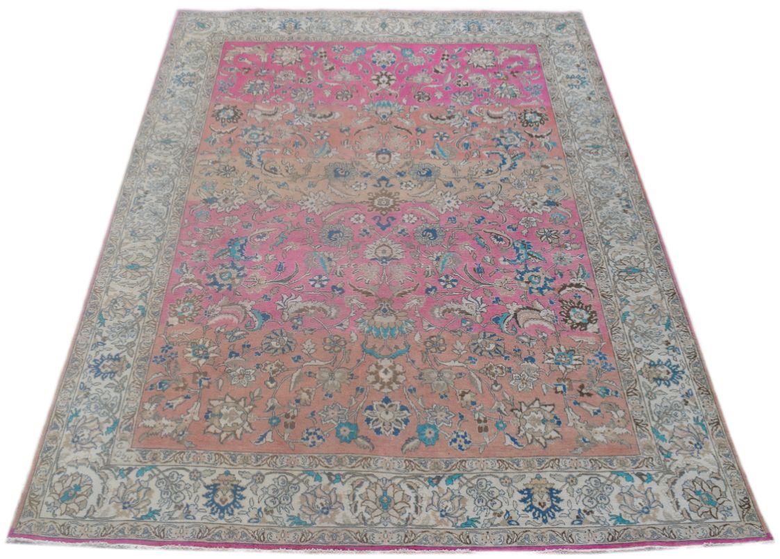 A rectangular vintage Persian wool rug featuring a floral pattern in shades of pink and blue.