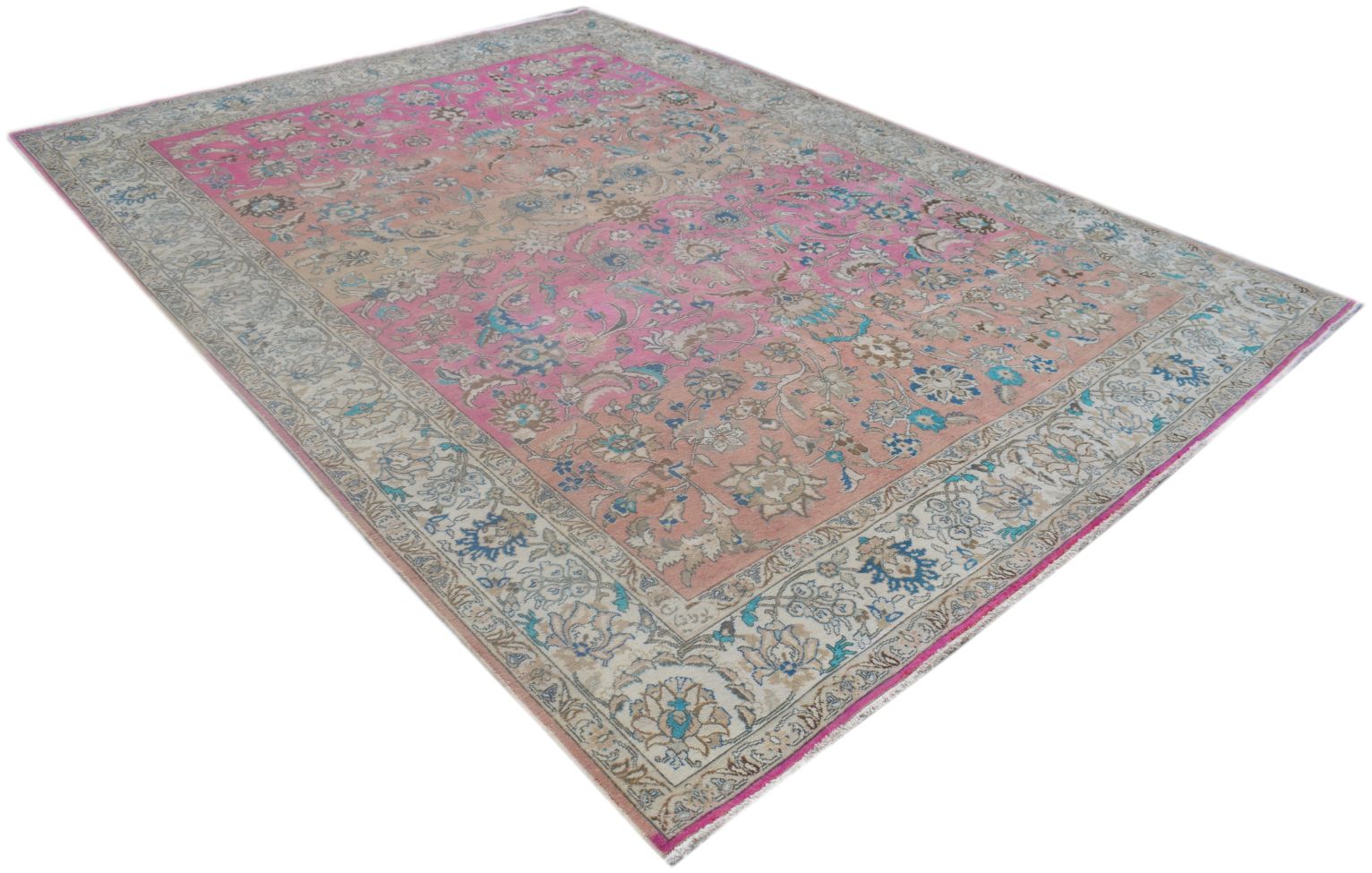 A vintage Persian rug featuring a floral pattern in shades of pink, blue, and cream.