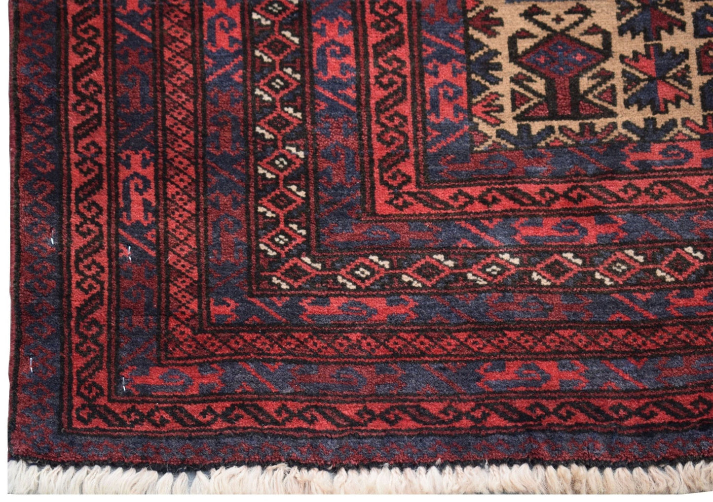 A vintage handmade Afghan Baluch rug featuring geometric patterns in deep red, blue, and ivory.