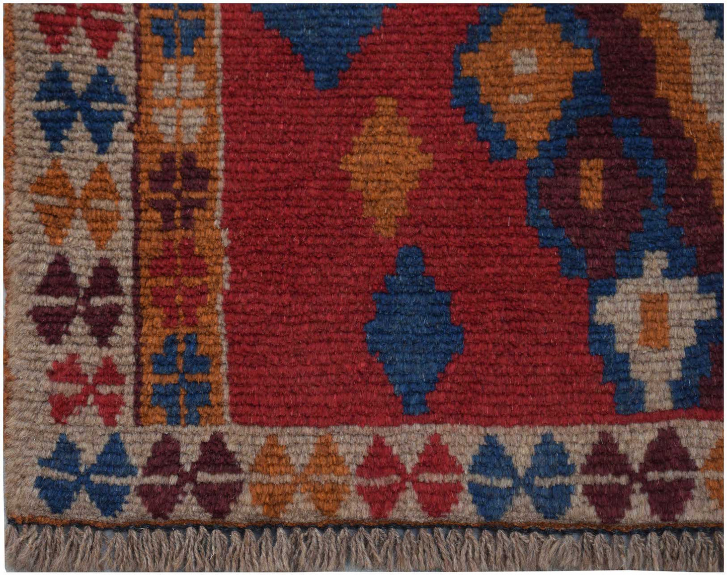 Handmade Afghan Pashm rug featuring a geometric tribal pattern in deep red, blue, and brown tones.