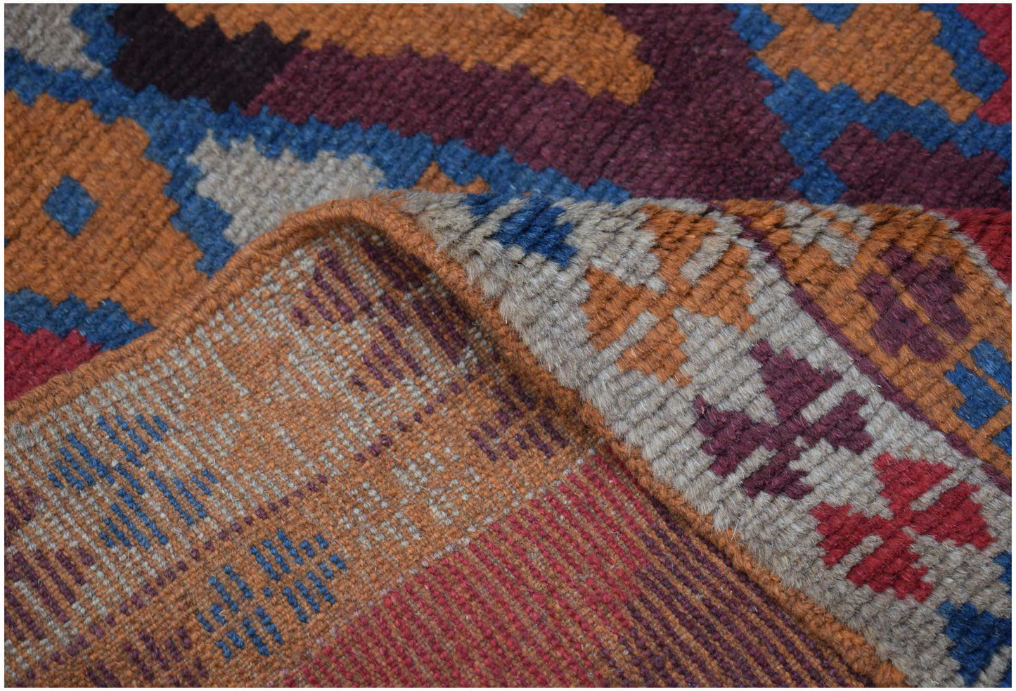 A handmade Afghan Pashm rug featuring a geometric tribal pattern in deep red, blue, and brown tones.