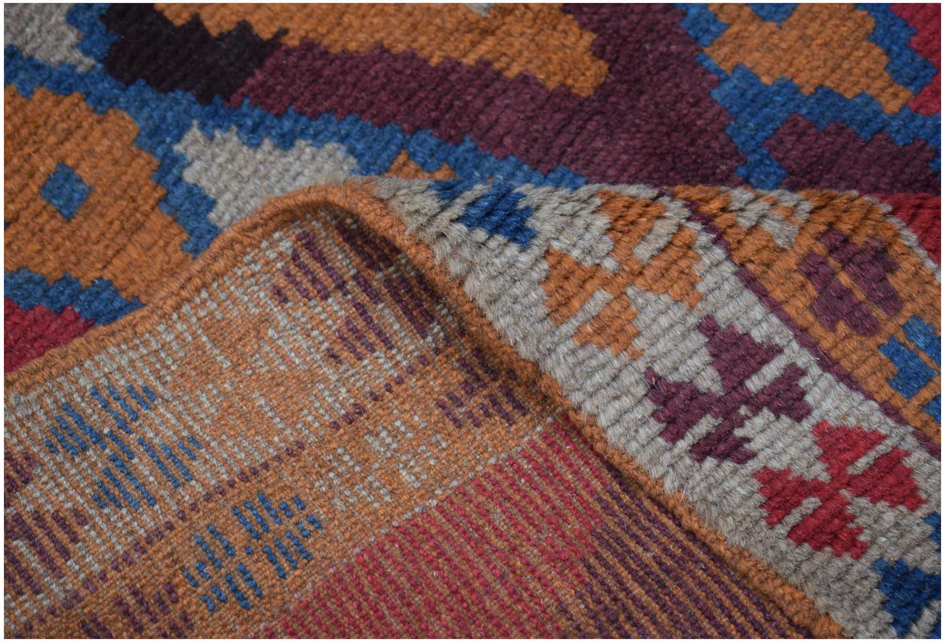 A handmade Afghan Pashm rug featuring a geometric tribal pattern in deep red, blue, and brown tones.