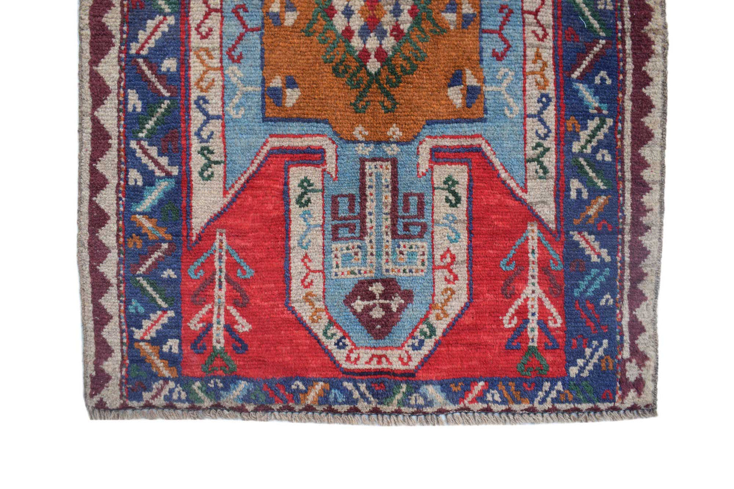 A handmade Afghan Pashm rug featuring a geometric tribal pattern in red, blue, and orange wool.