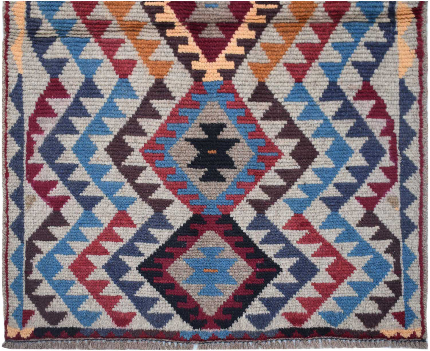 Handmade Afghan Pashm rug featuring a geometric tribal pattern in shades of red, blue, and brown.