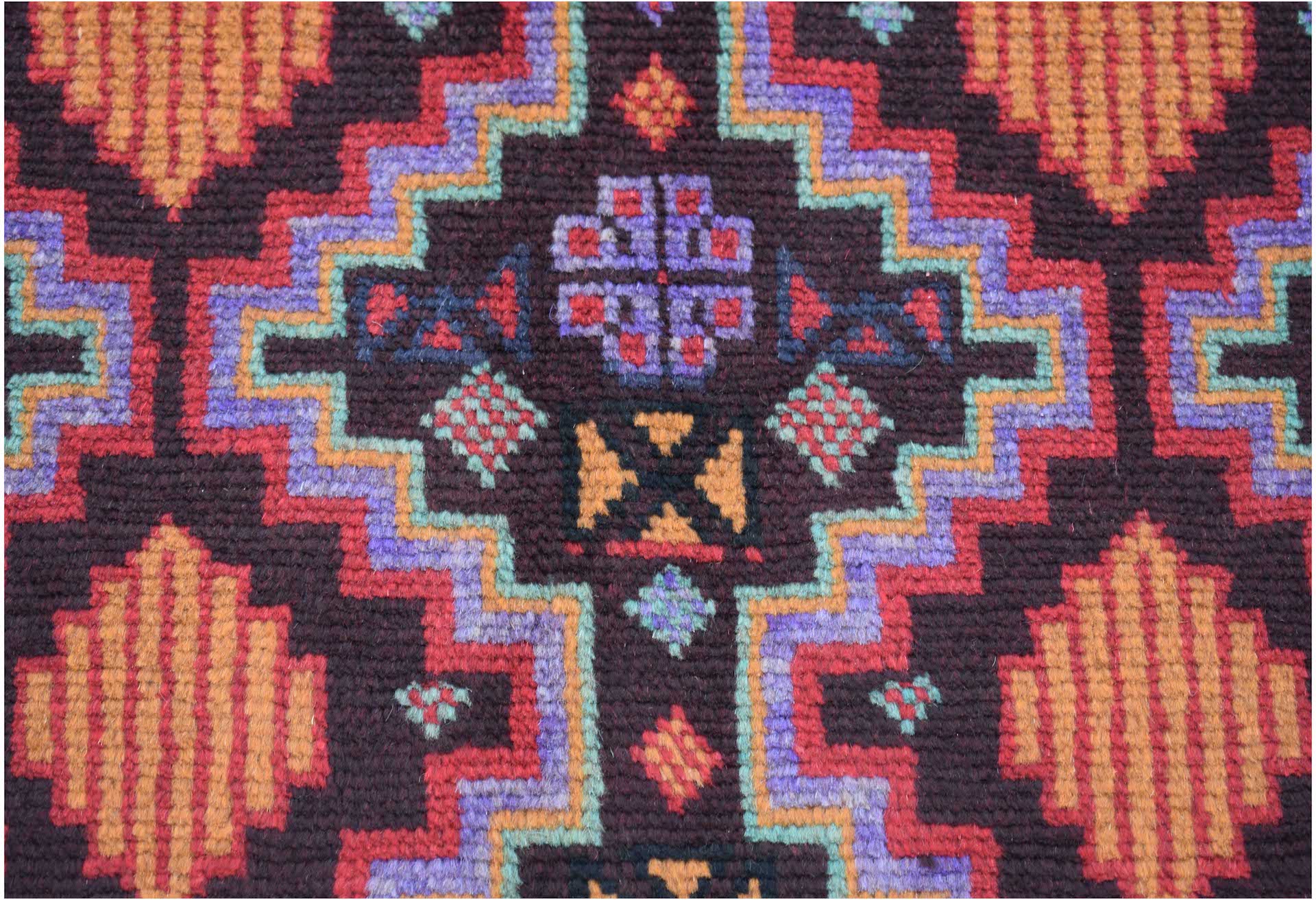Handmade Afghan Pashm rug featuring a geometric tribal pattern in dark red, blue, and orange tones.