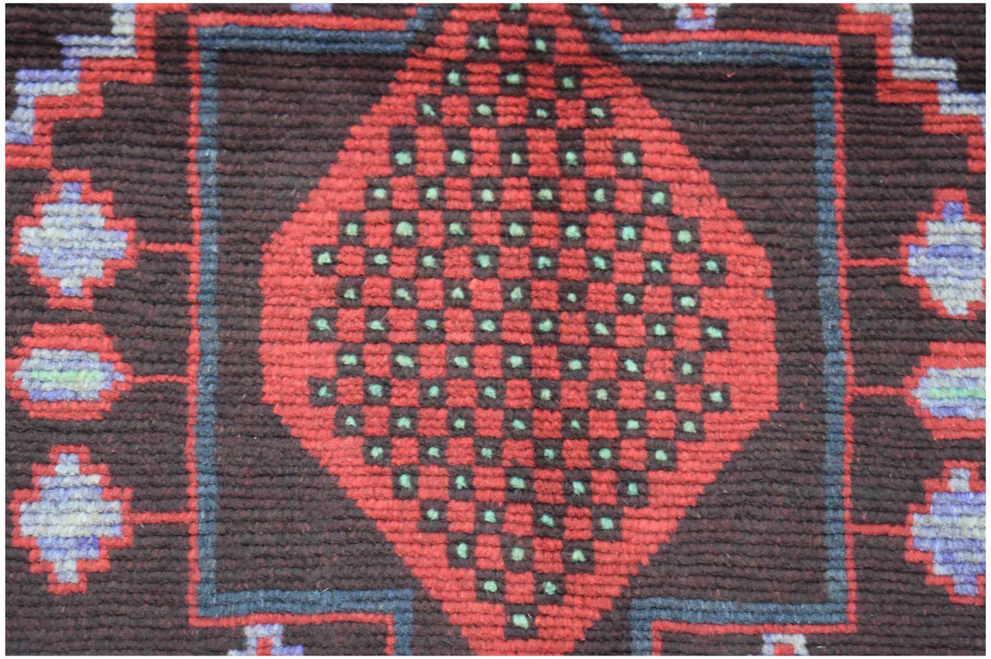 Handmade Afghan wool rug featuring a central red diamond pattern with green accents on a dark field.