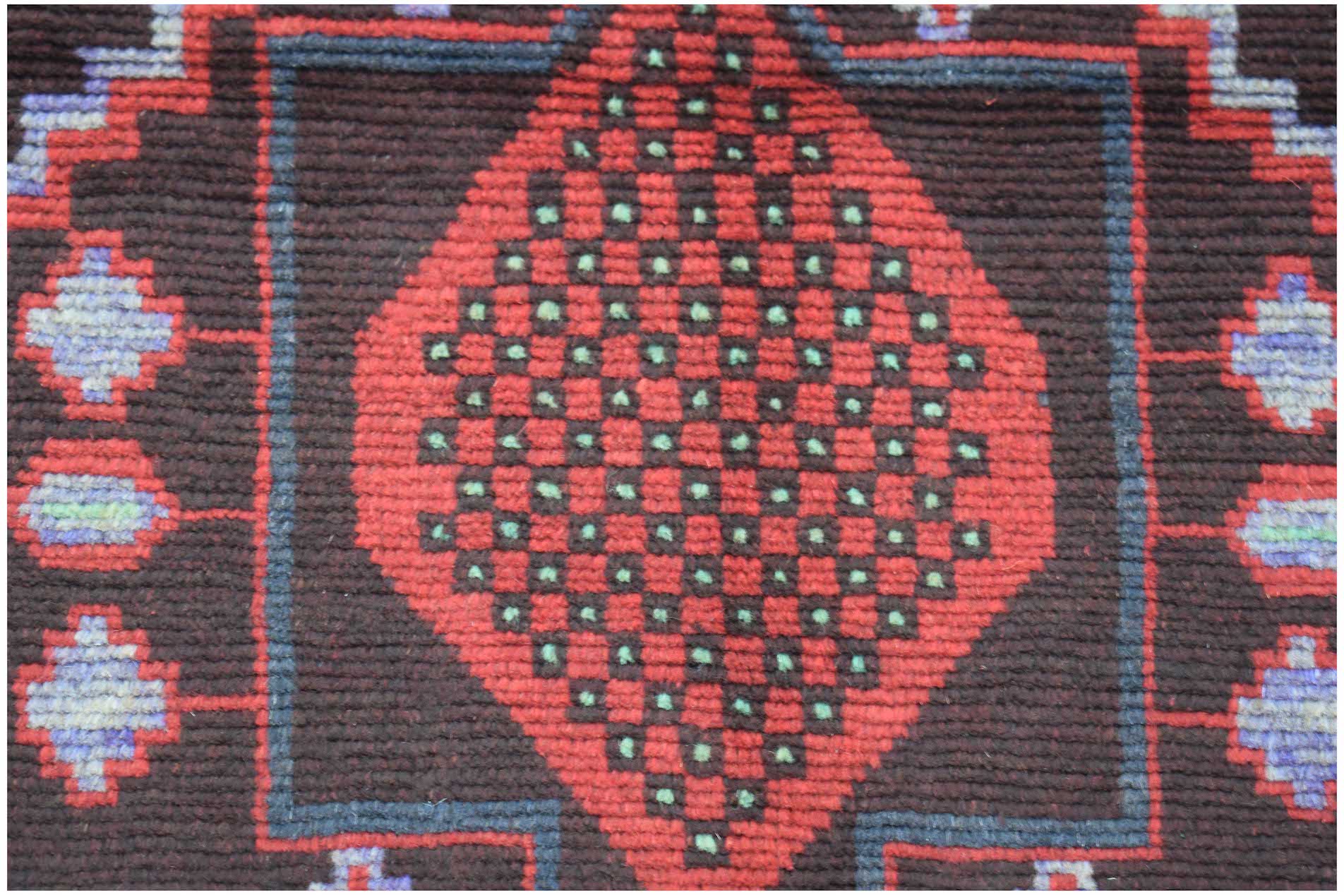 Handmade Afghan wool rug featuring a central red diamond pattern with green accents on a dark field.