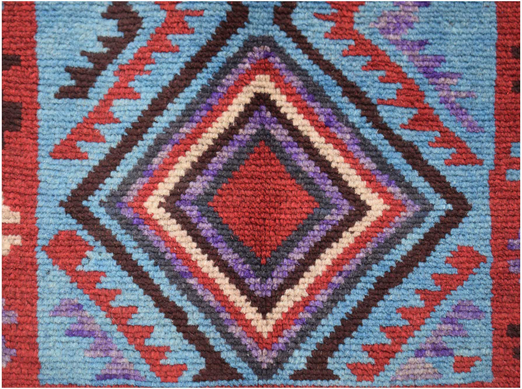 A handmade Afghan Pashm rug featuring a central diamond pattern in red, blue, brown, and ivory.