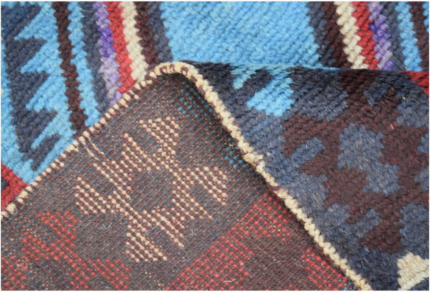 A handmade Afghan Pashm rug featuring a geometric pattern in shades of blue, red, and brown.