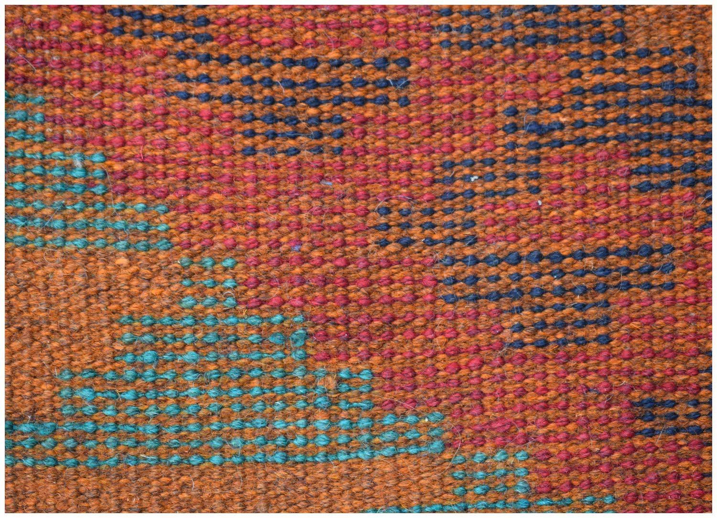 Close-up of a handmade Afghan Pashm rug featuring a geometric pattern in red, blue, and brown wool.