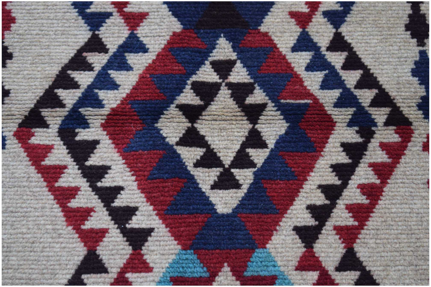 Handmade Afghan Pashm rug featuring a geometric diamond pattern in red, blue, and ivory wool.