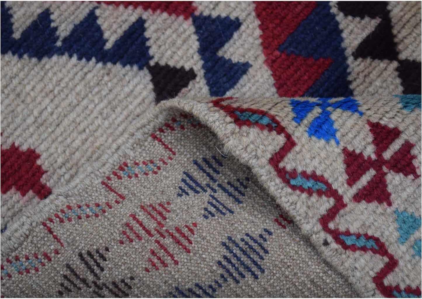A handmade Afghan Pashm rug featuring geometric patterns in red, blue, and ivory wool.