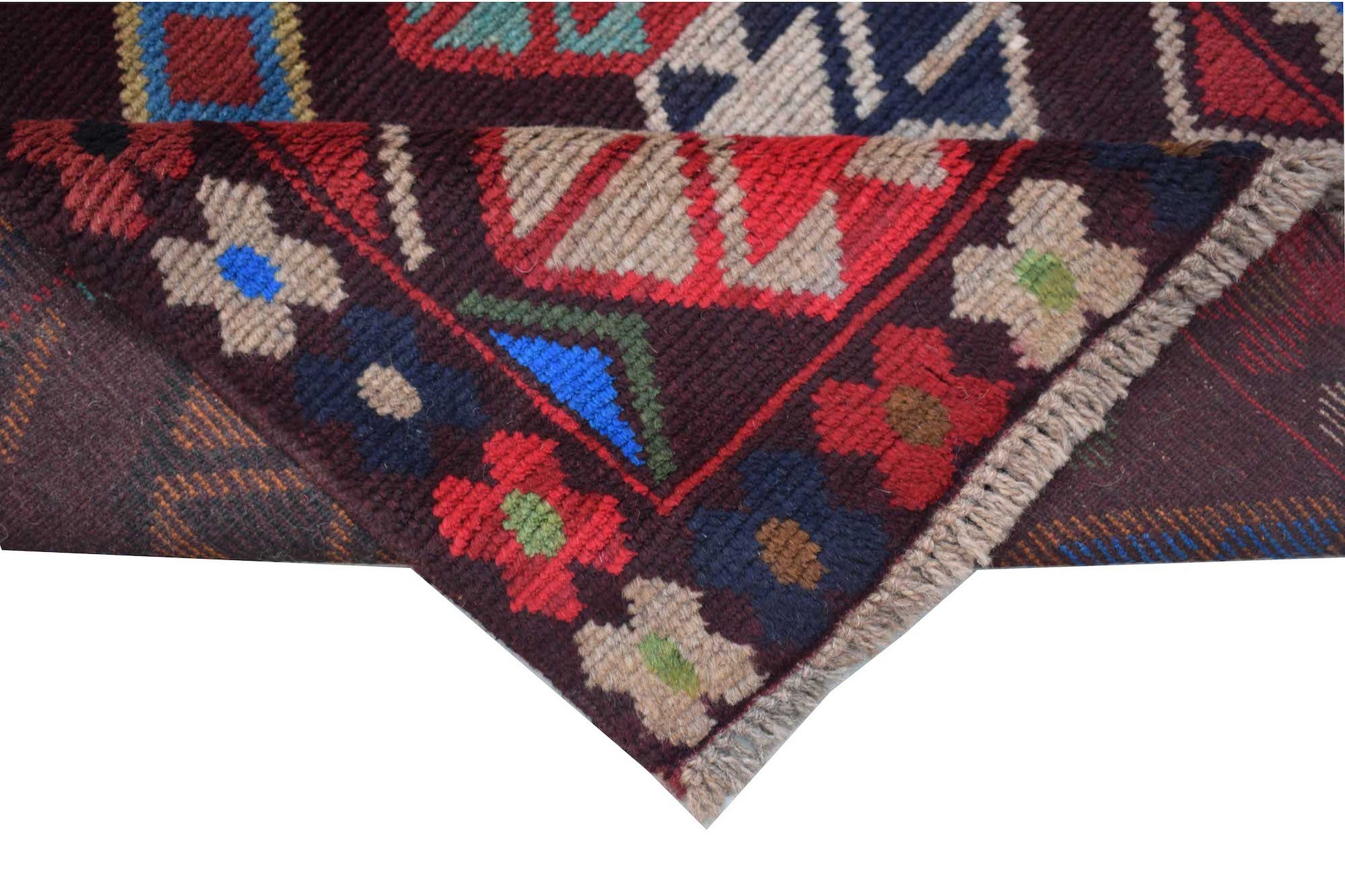 A handmade Afghan Pashm rug featuring traditional tribal geometric patterns in deep red, blue, and brown.