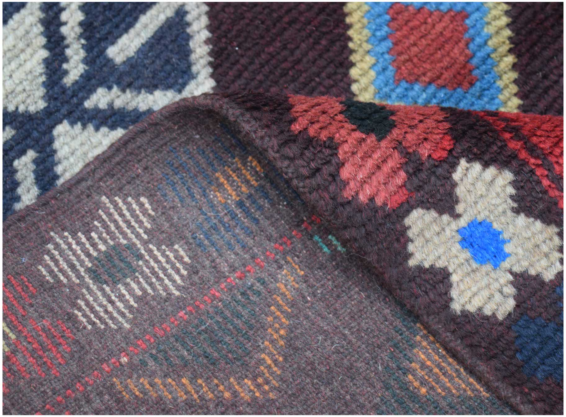 A handmade Afghan Pashm rug featuring a dark brown base with geometric patterns in red and blue.
