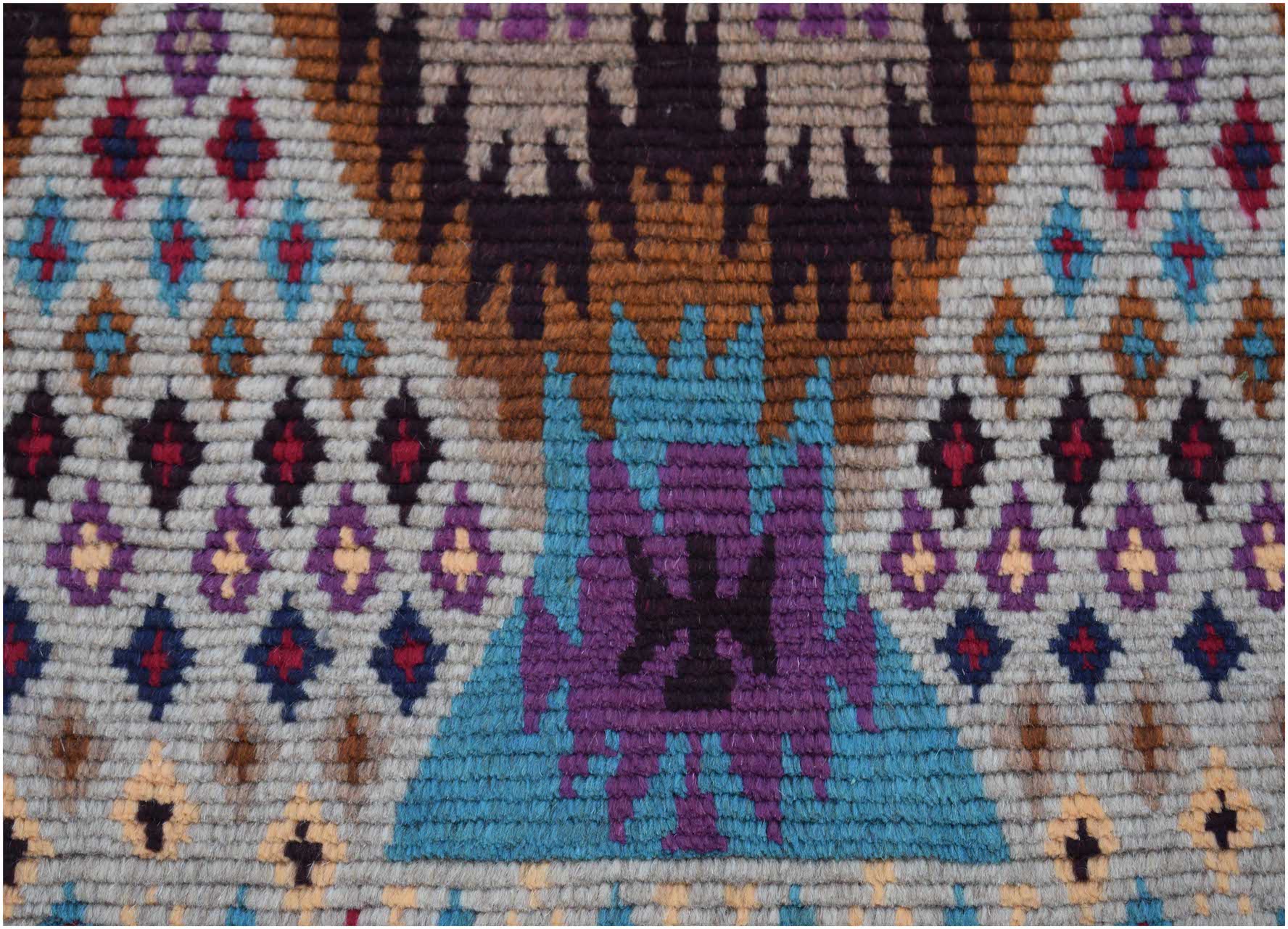 Handmade Afghan Pashm rug featuring a geometric tribal pattern in blue, purple, and brown tones.