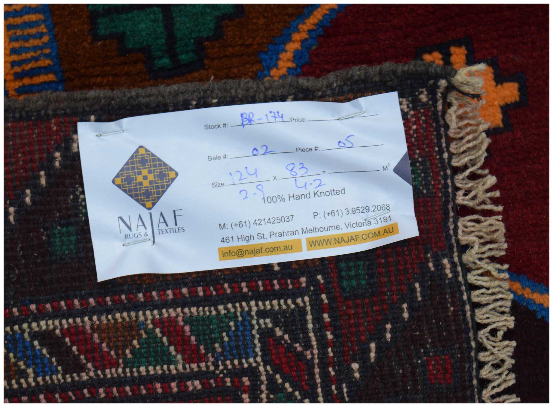 A handmade Afghan Pashm rug featuring a tribal pattern in dark red, brown, and blue tones.