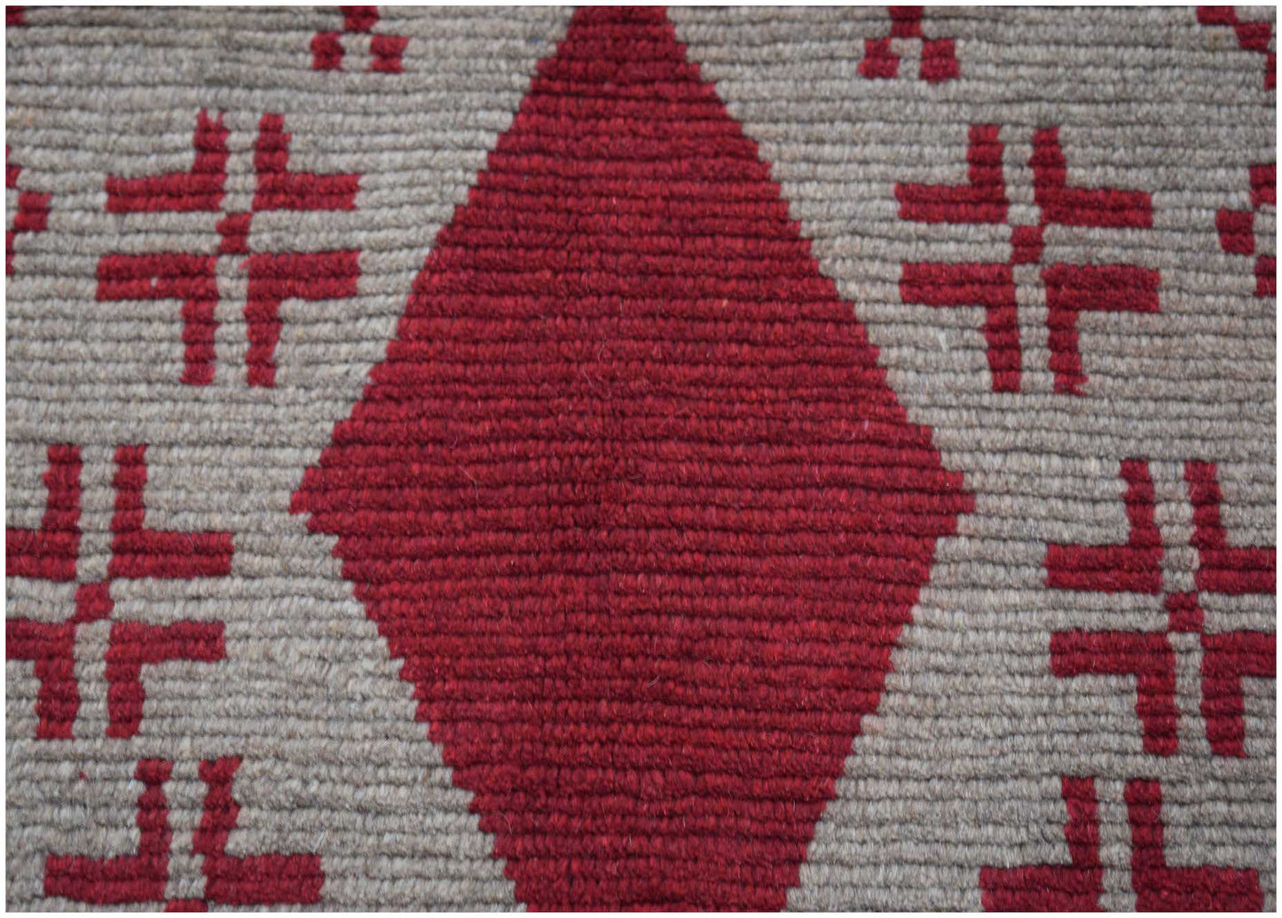 Handmade Afghan Pashm rug featuring a large red diamond pattern on a textured beige wool background.