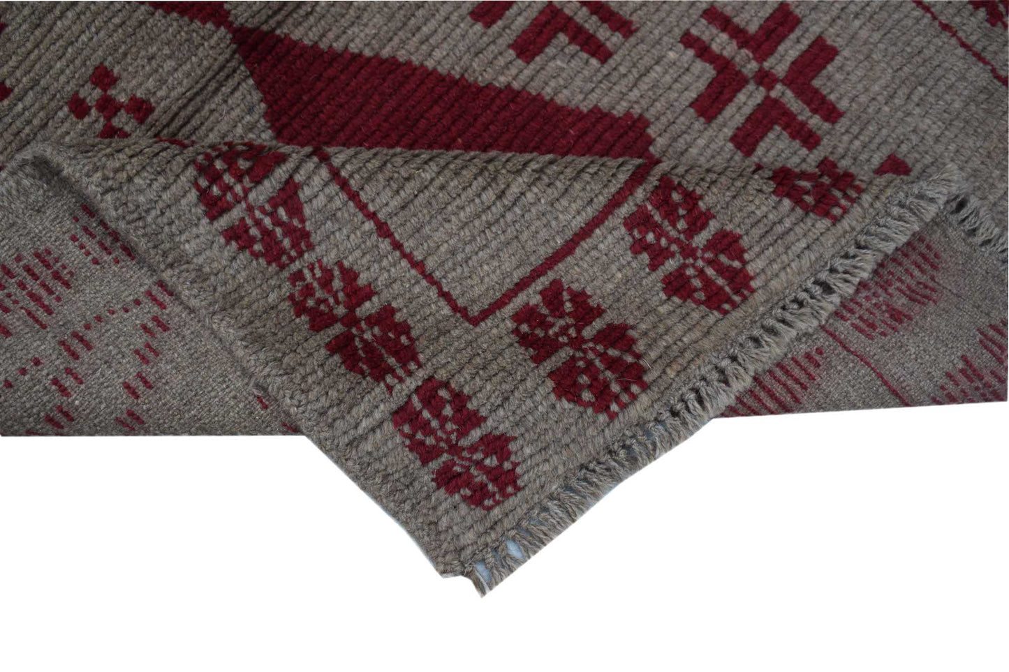 A handmade Afghan Pashm rug featuring a geometric tribal pattern in deep red on a brown wool base.