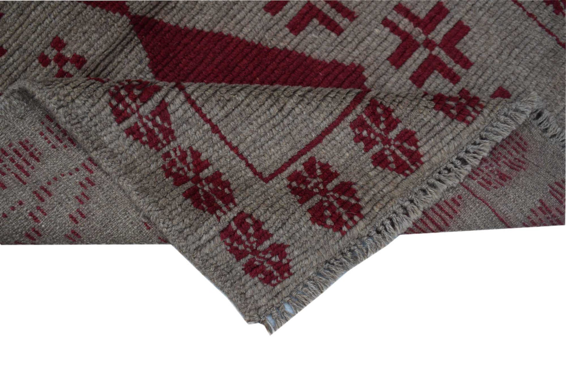 A handmade Afghan Pashm rug featuring a geometric tribal pattern in deep red on a brown wool base.
