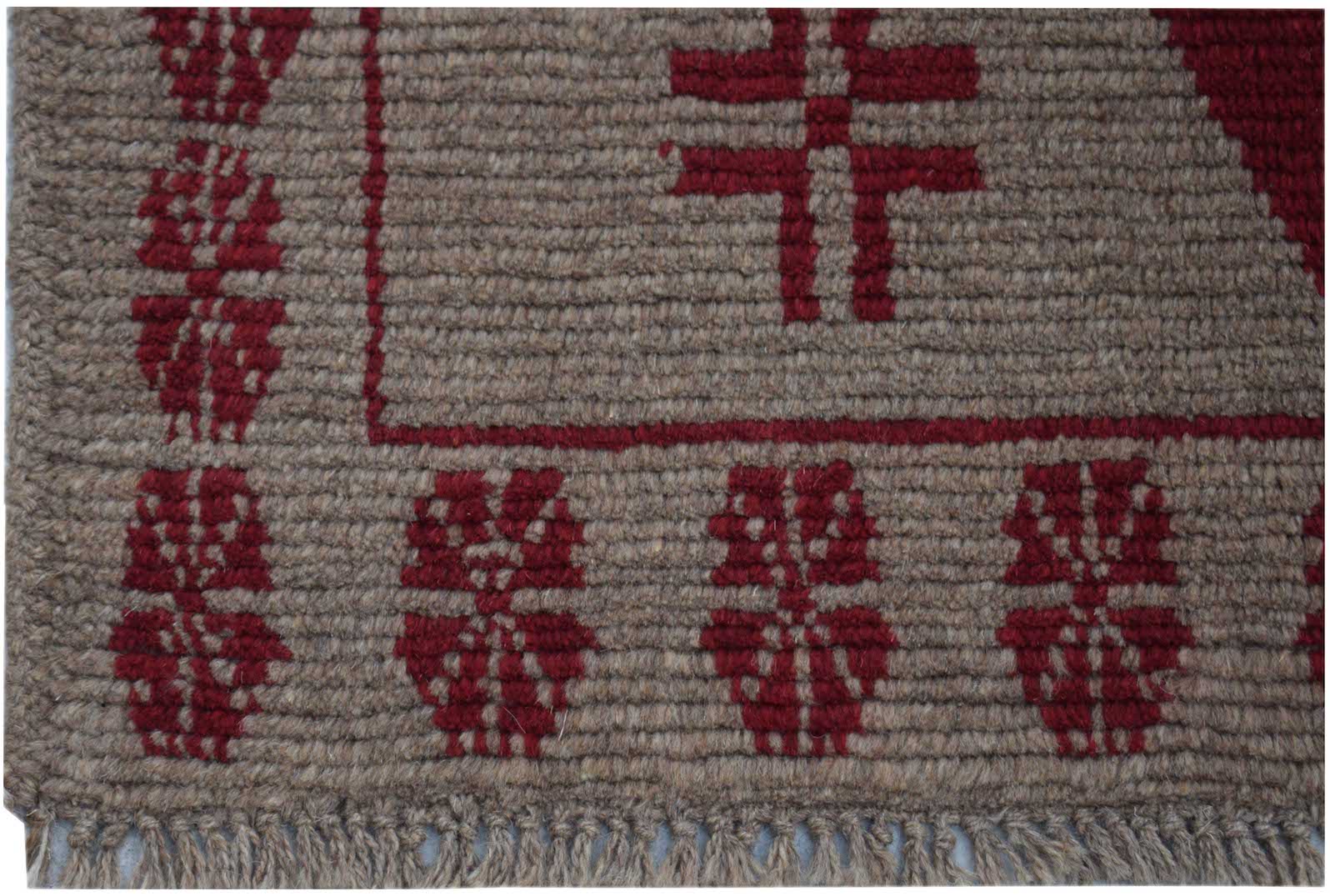 A handmade Afghan Pashm rug featuring a brown wool base with geometric red tribal patterns.