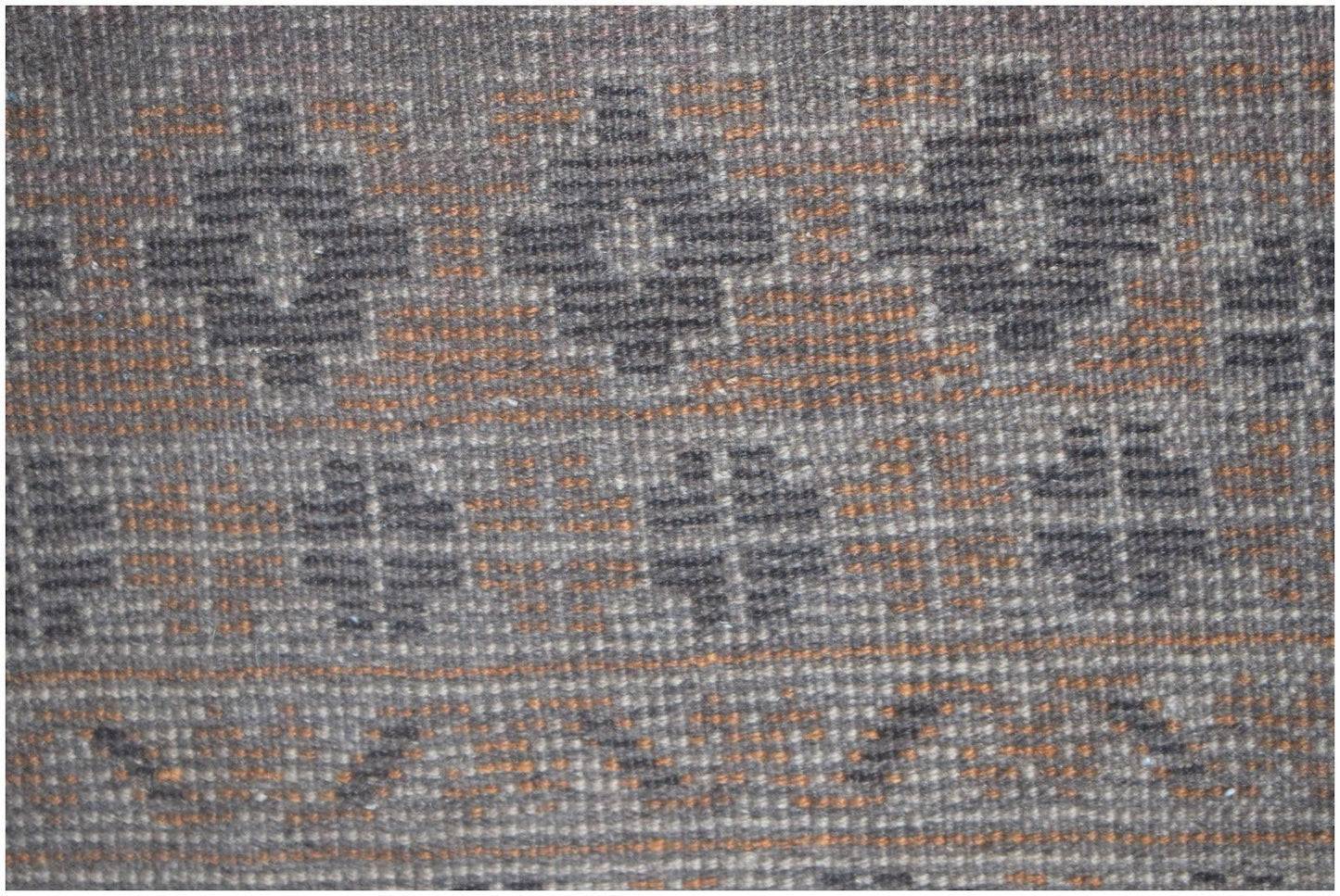 A close-up of a vintage Afghan Baluch rug featuring geometric patterns in brown and orange wool.