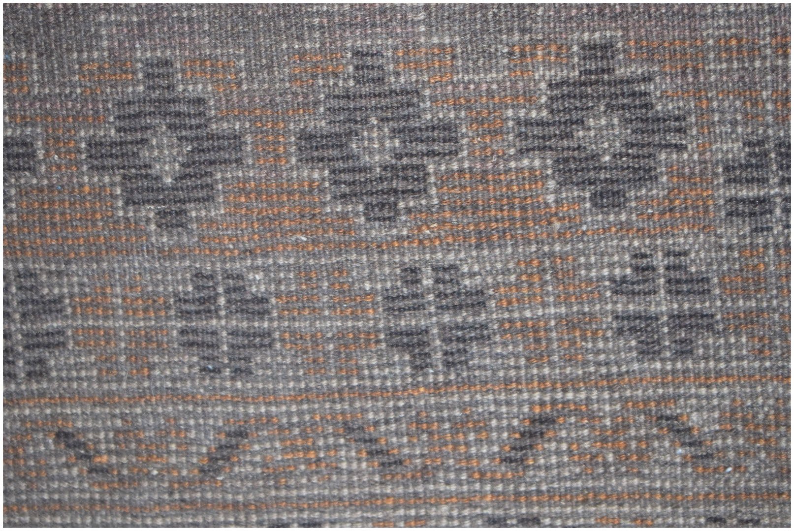 A close-up of a vintage Afghan Baluch rug featuring geometric patterns in brown and orange wool.