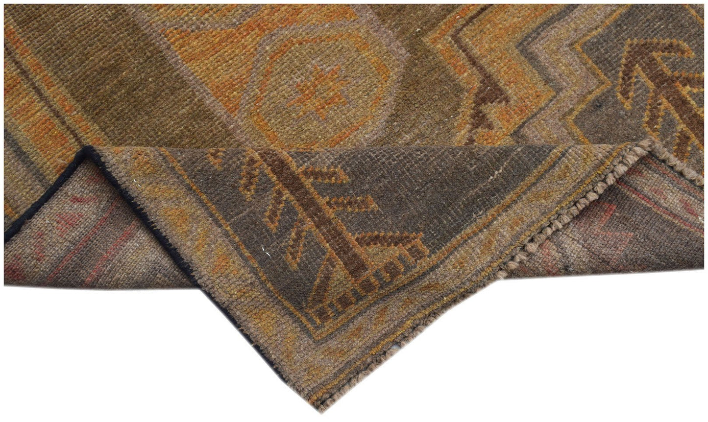A handmade Afghan Baluch rug featuring geometric patterns in shades of brown and orange.