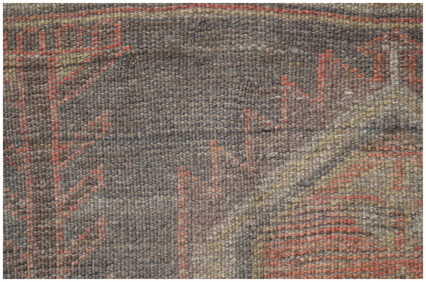 A close-up of a handmade Afghan Baluch wool rug featuring geometric patterns in red and brown.