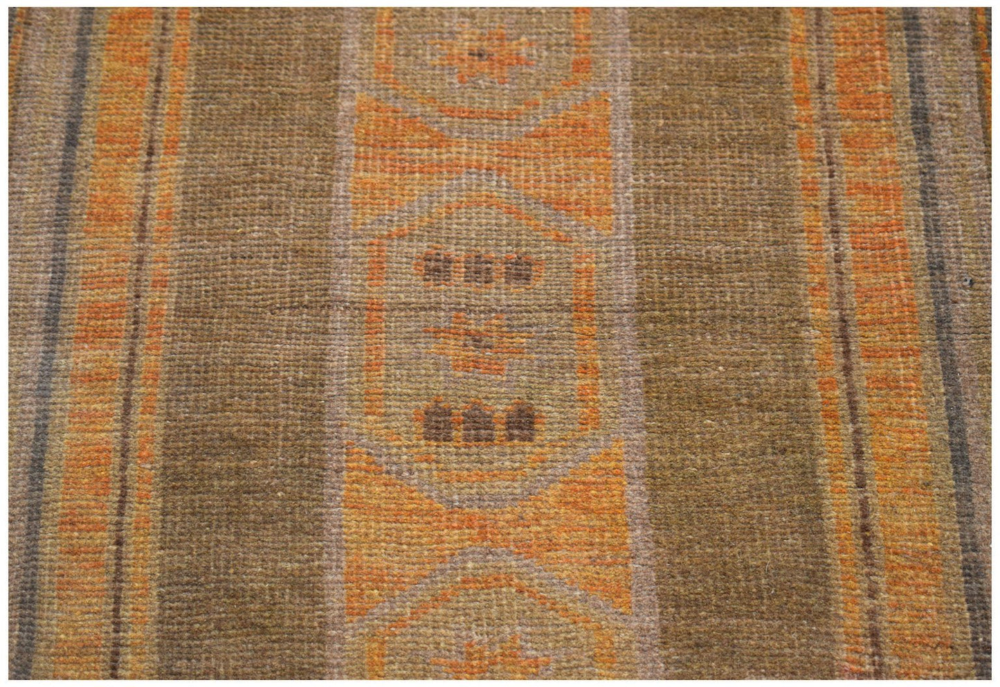 A handmade Afghan Baluch rug featuring geometric patterns in shades of brown and orange.