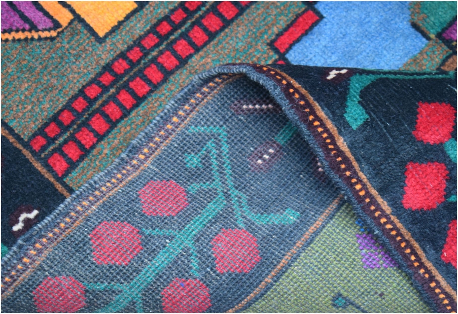 A handmade Afghan Baluch wool rug featuring geometric patterns in dark red, blue, and brown tones.