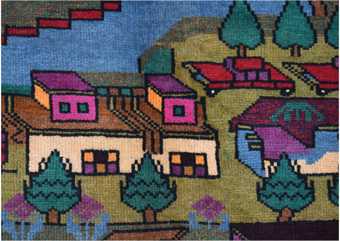 A handmade Afghan Baluch rug featuring a detailed, colorful village landscape with trees and houses.