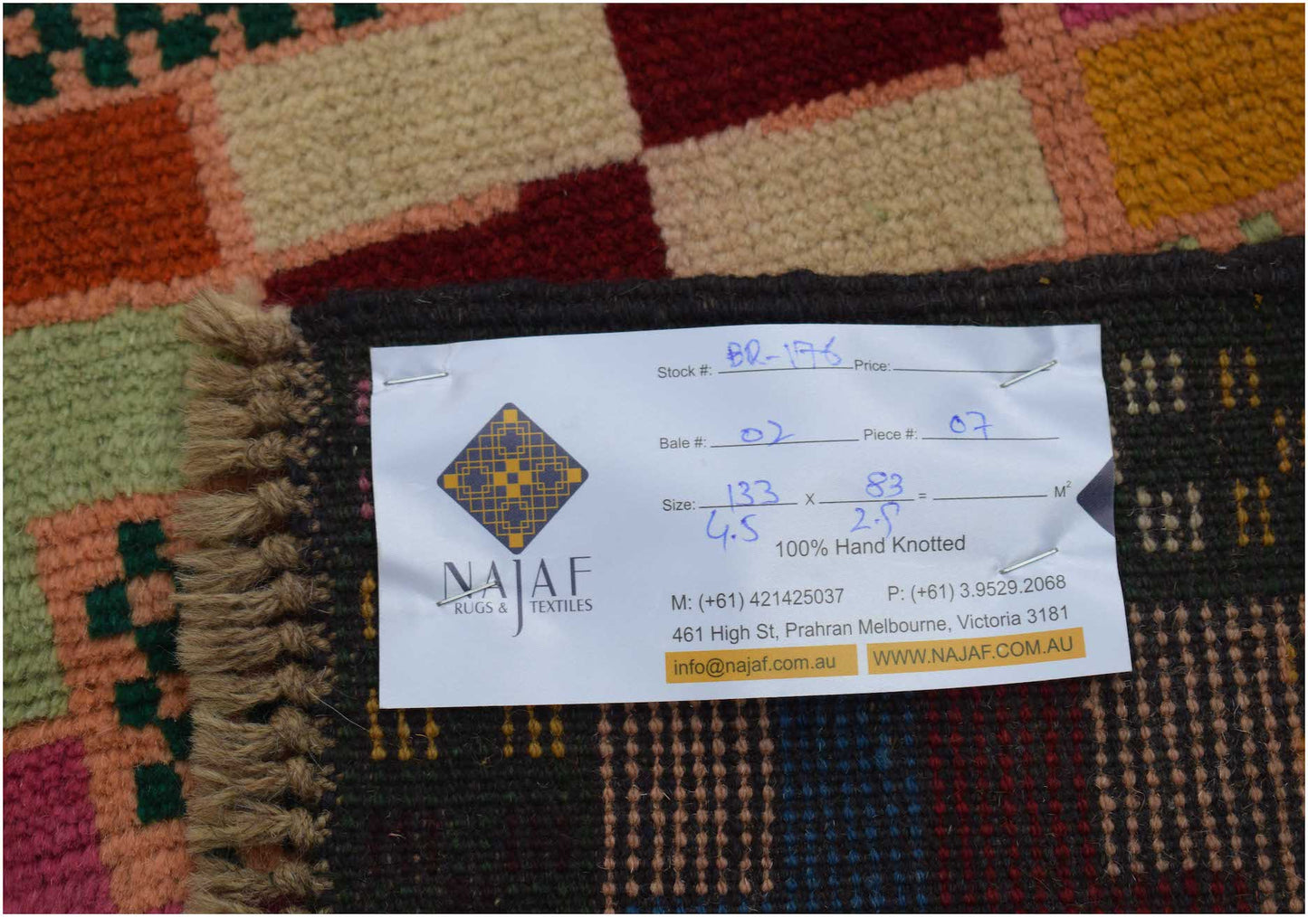 A handmade Afghan Pashm rug featuring a geometric pattern of colorful squares in wool.
