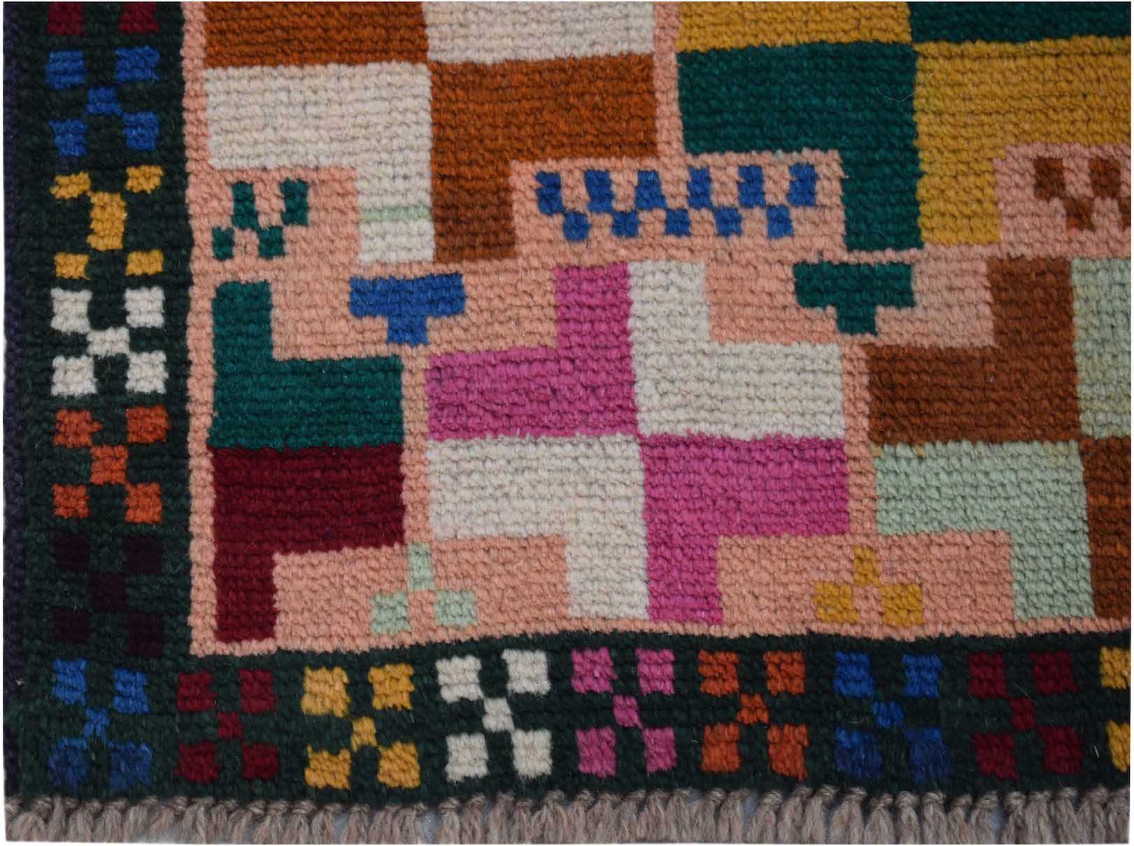 A handmade Afghan Pashm rug featuring a geometric pattern of colorful squares on a pink background.