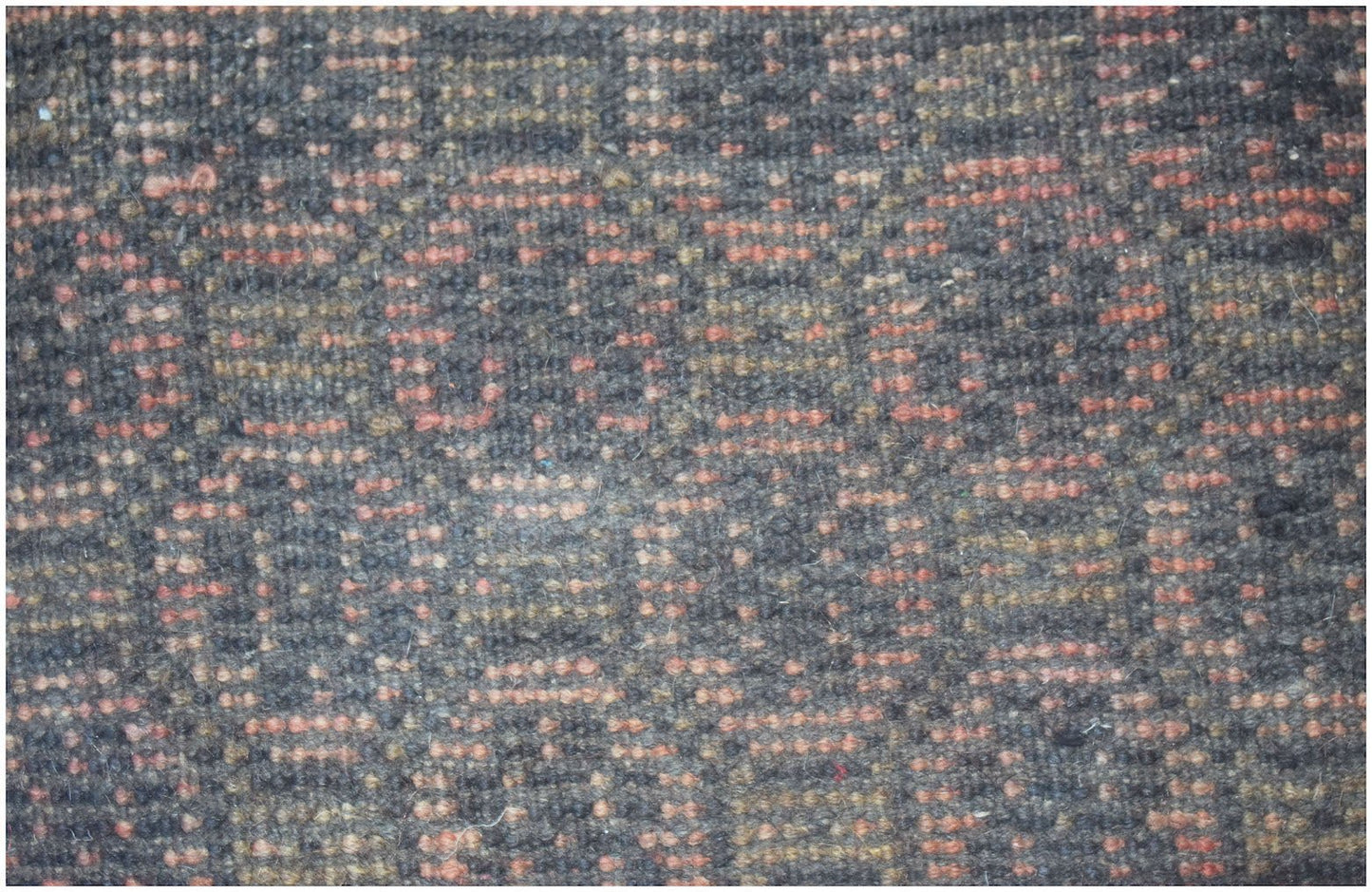 A close-up of a handmade Afghan Baluch rug featuring a geometric pattern in dark and red wool.