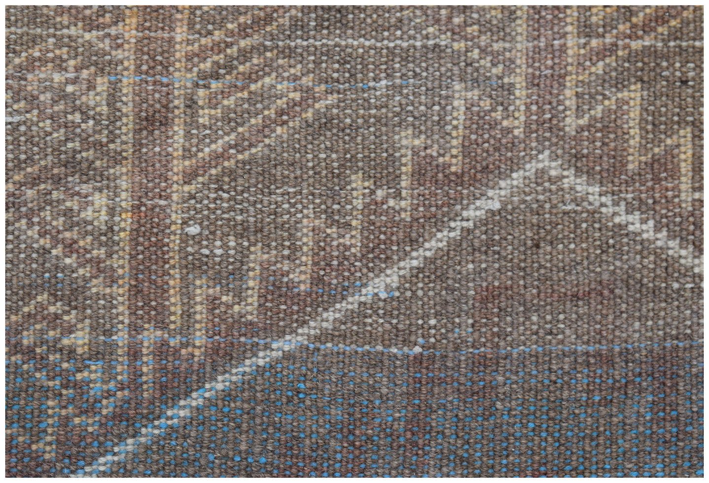 A close-up of a handmade Afghan Baluch rug featuring geometric patterns in brown, blue, and cream.