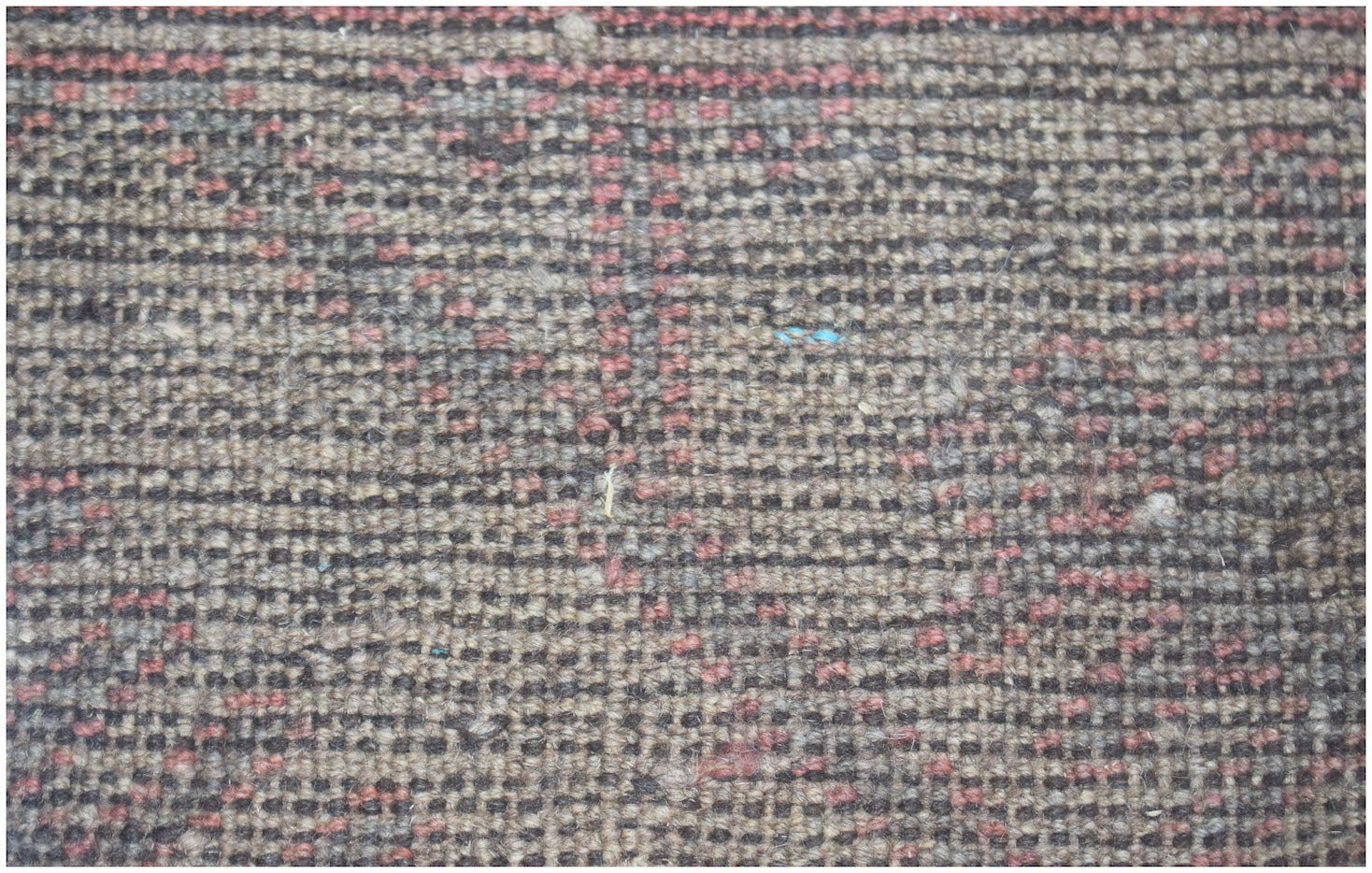 A close-up of a handmade Afghan Baluch rug featuring a textured, geometric pattern in wool.