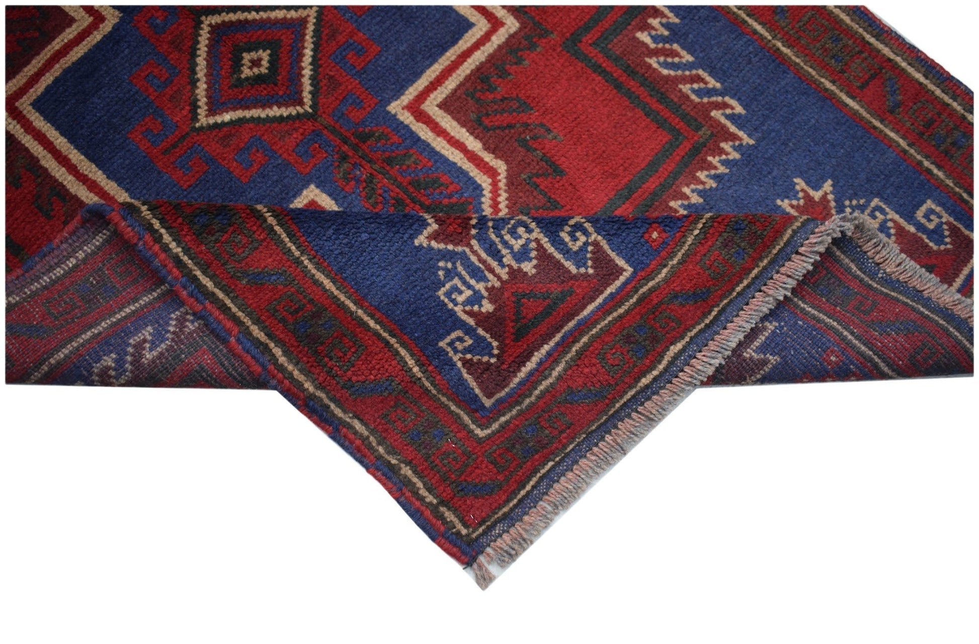 A handmade Afghan Baluch rug featuring geometric patterns in deep red, blue, and ivory tones.