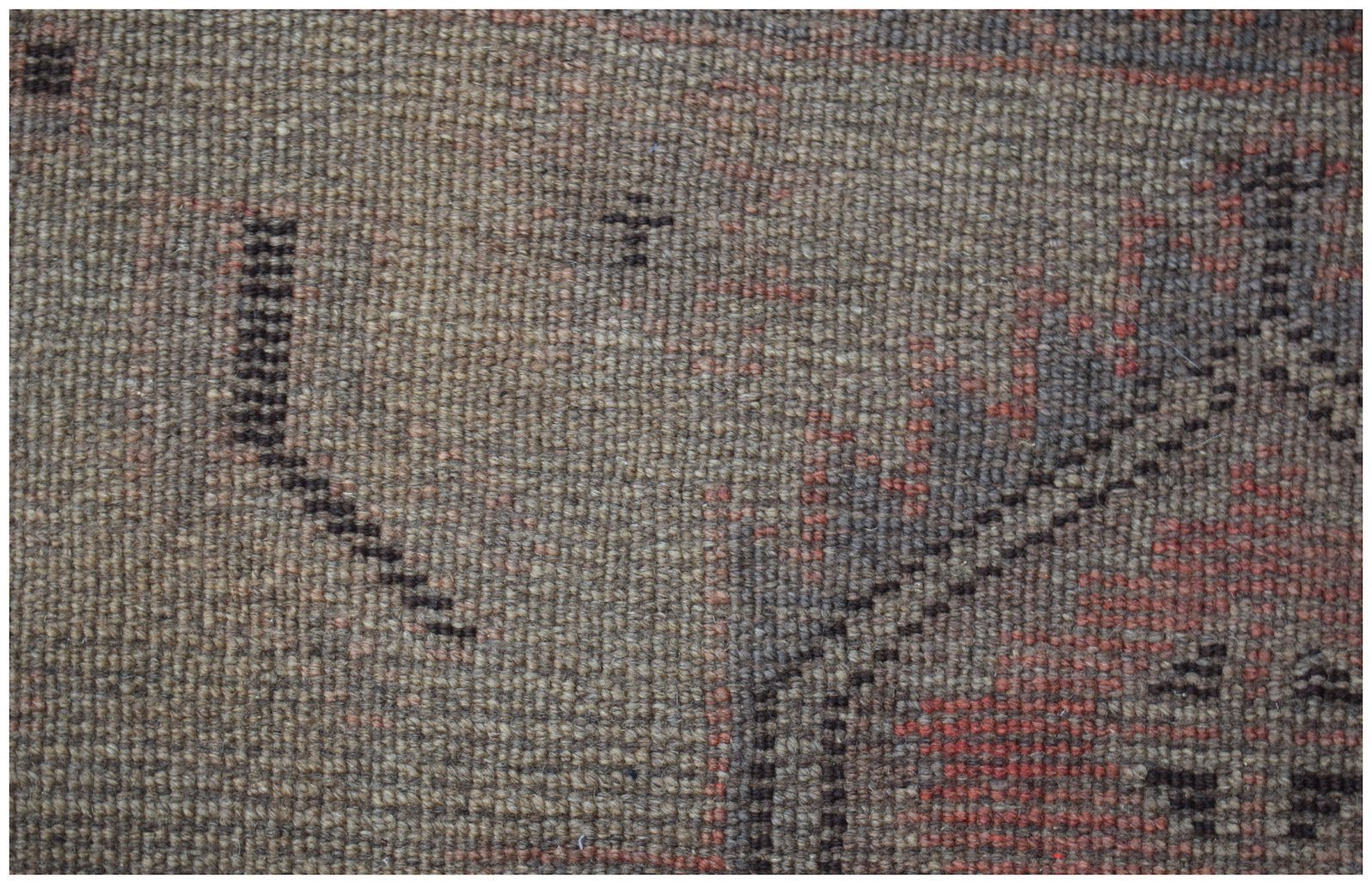 A close-up of a handmade Afghan Baluch rug featuring geometric patterns in brown and red wool.