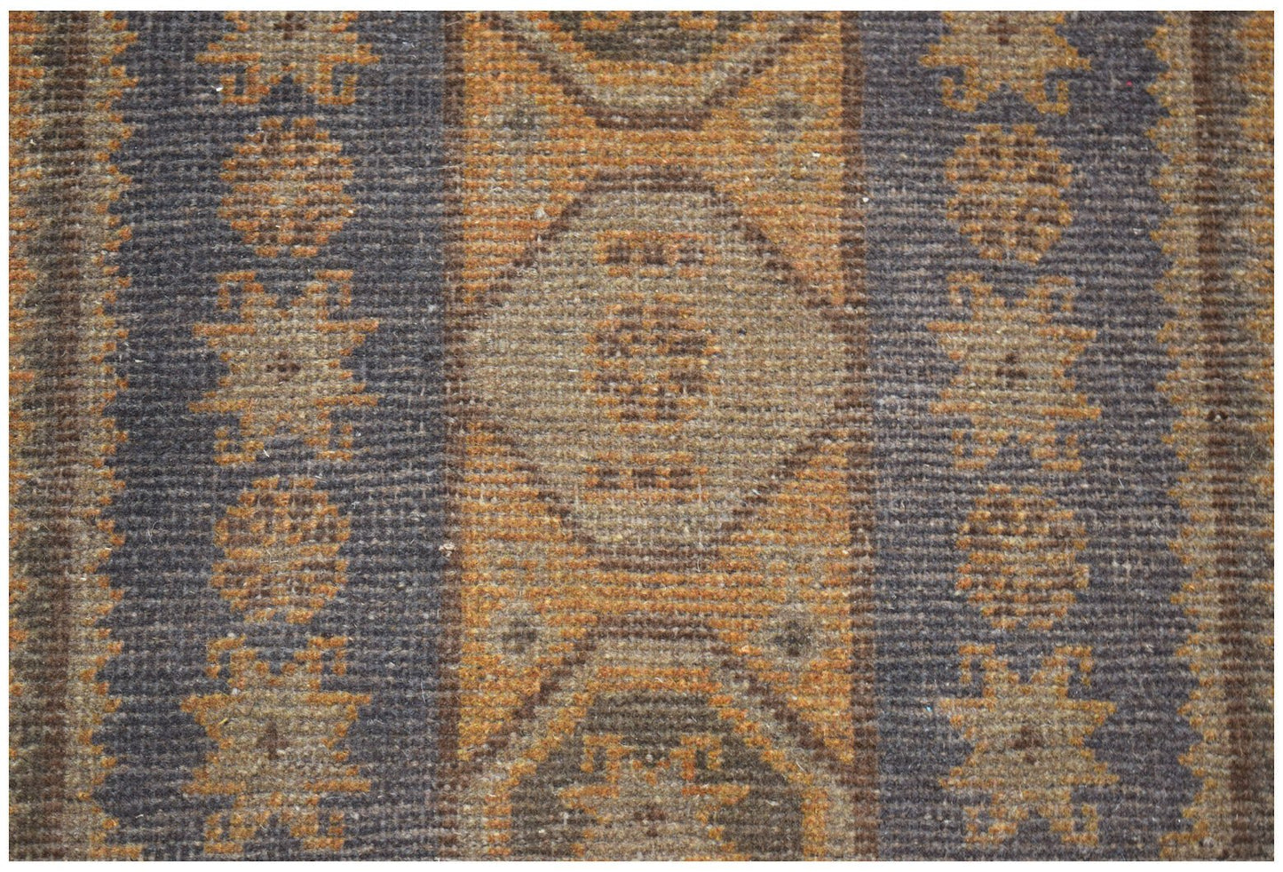 A handmade Afghan Baluch rug featuring geometric patterns in shades of brown and orange.