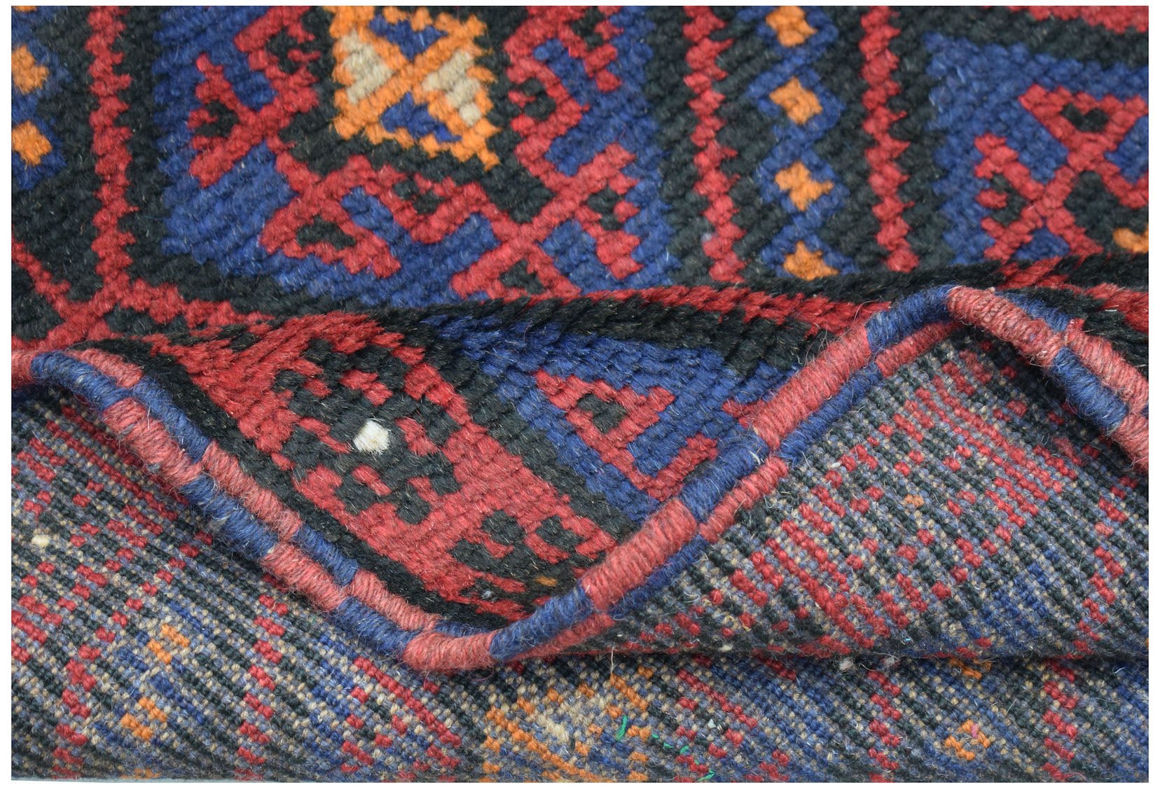 A handmade Afghan Baluch rug featuring a geometric pattern in deep red, blue, and orange wool.