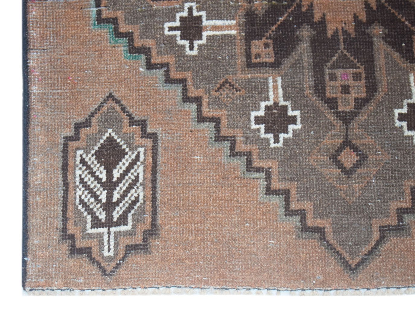 A handmade Afghan Baluch rug featuring geometric patterns in brown and cream wool.