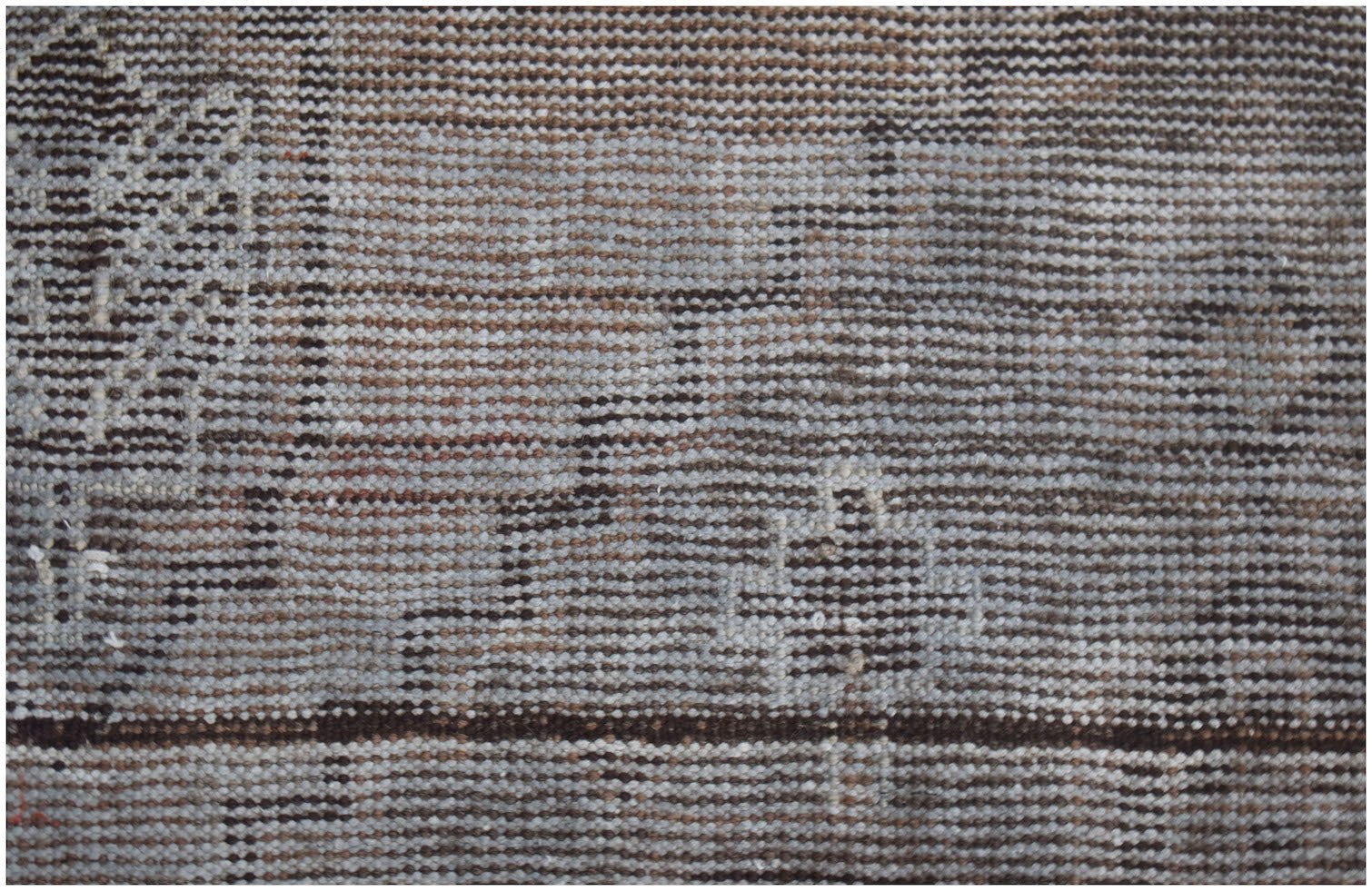 A close-up of a handmade Afghan Baluch rug featuring a geometric pattern in brown and cream wool.