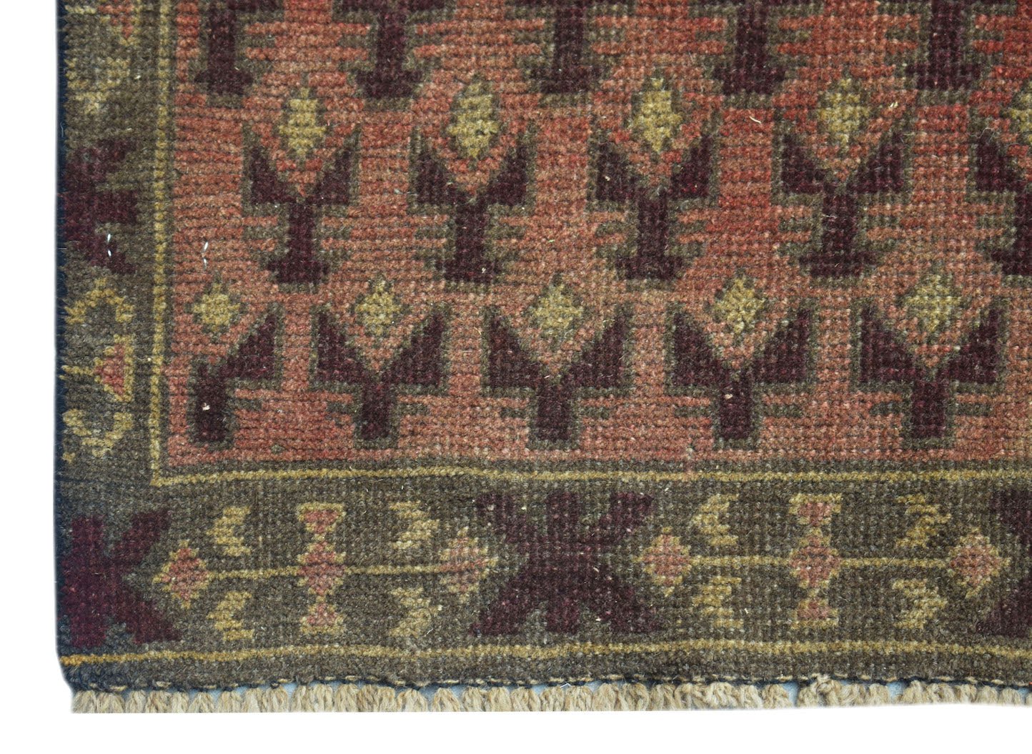 A handmade Afghan Baluch rug featuring a geometric pattern in shades of red, brown, and tan.