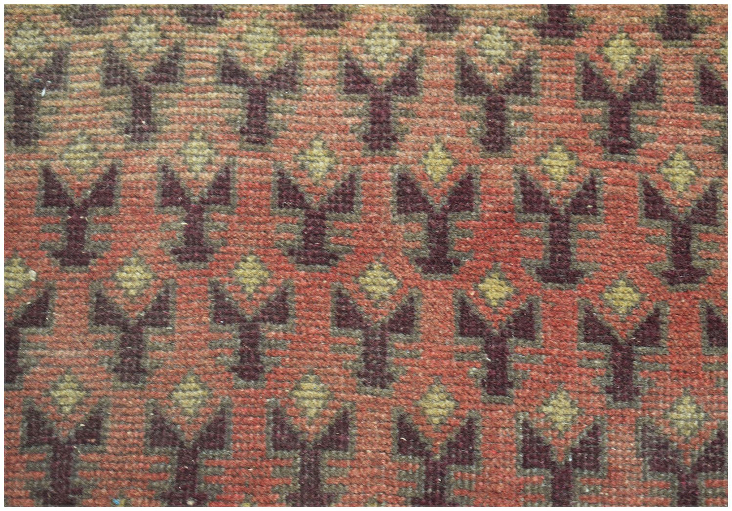 Handmade Afghan Baluch rug featuring a repeating dark brown and tan floral pattern on a red field.