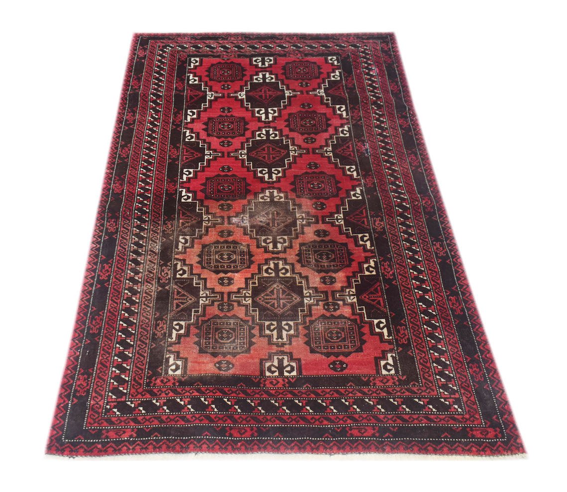 A handmade vintage Afghan Baluch rug featuring a geometric pattern in shades of red and black.