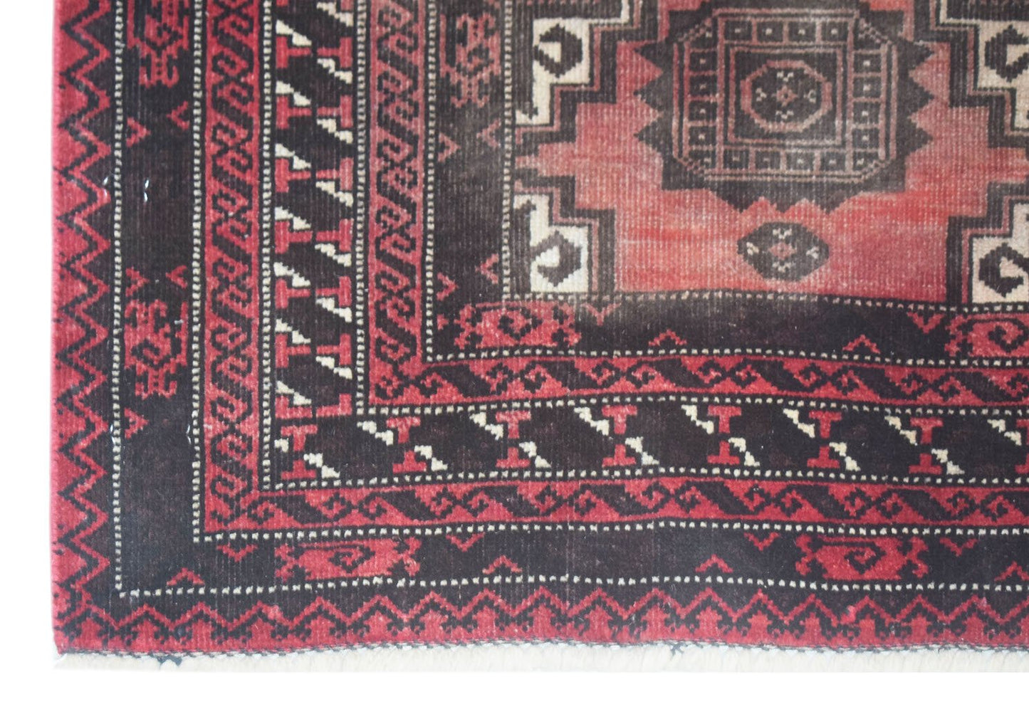 A vintage handmade Afghan Baluch rug featuring geometric patterns in red and black wool.