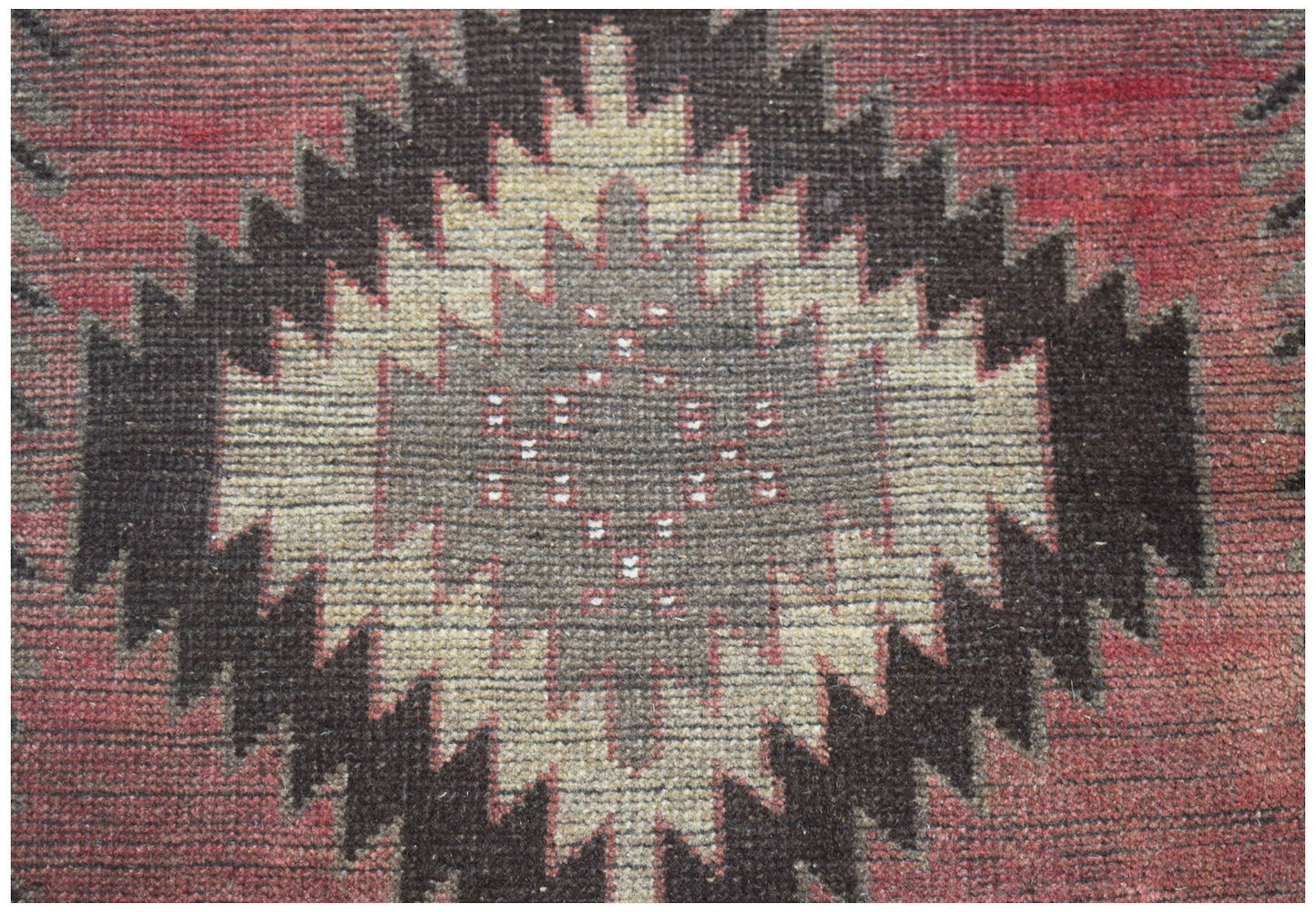A handmade Afghan Baluch rug featuring a central diamond motif in shades of red, brown, and tan.
