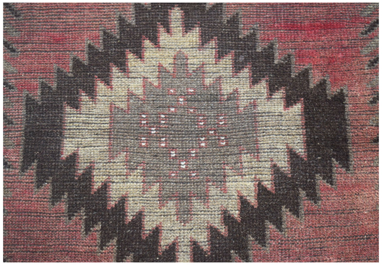 A handmade Afghan Baluch rug featuring a central diamond motif in shades of red, brown, and tan.