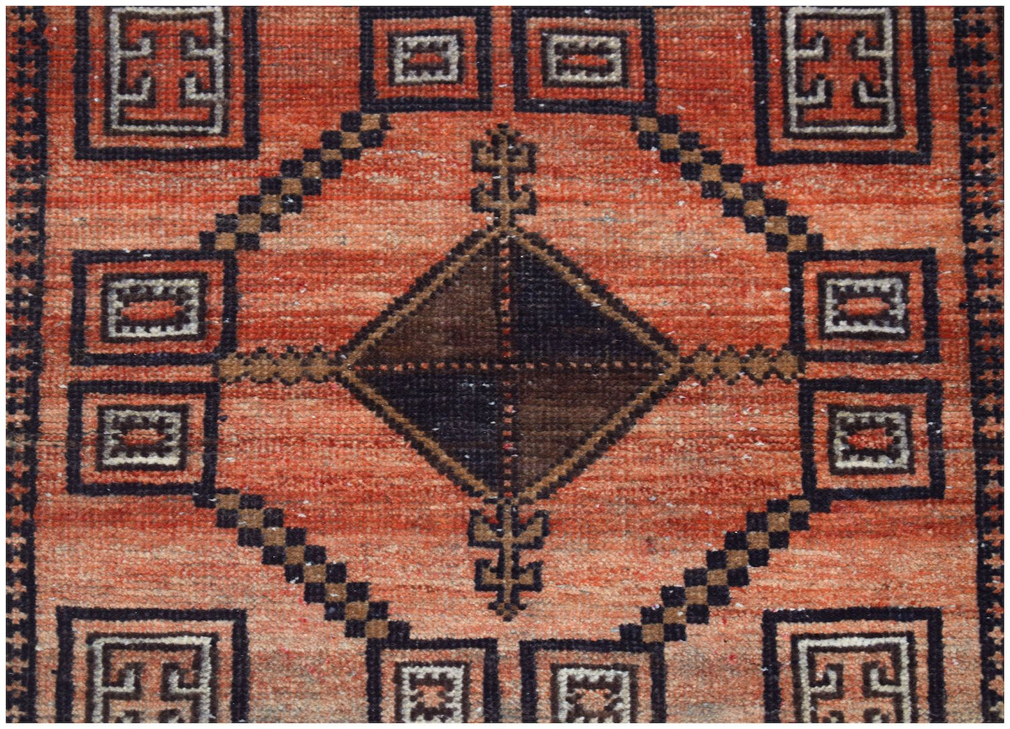Handmade Afghan Baluch rug featuring a central dark diamond motif on a textured orange background.
